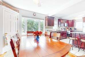 A dining area with a wooden table, chairs, and a vase of flowers.