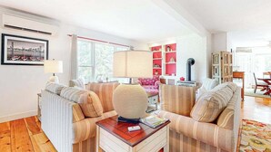 A living room with striped sofas, a coffee table, a lamp, and a bookshelf.