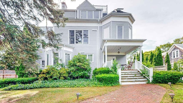 A large, two-story house with a prominent front porch and a brick pathway leading to the entrance.