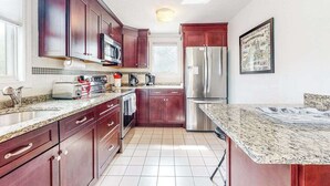 A kitchen with dark wooden cabinets, a stainless steel refrigerator, a microwave, and a granite countertop.