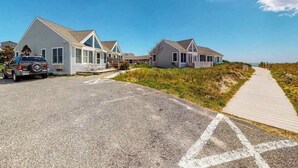Une propriété située sur la côte, comprenant plusieurs maisons, une route asphaltée et une promenade en bois.
