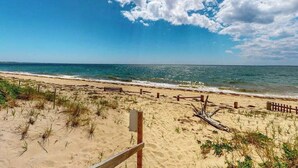 Une plage avec une clôture en bois, un poteau en bois et un panneau.