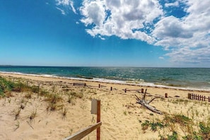 A beach with a wooden fence, a wooden post, and a sign.