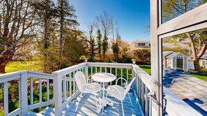 Une terrasse avec une table et des chaises, entourée d’arbres et d’une pelouse.