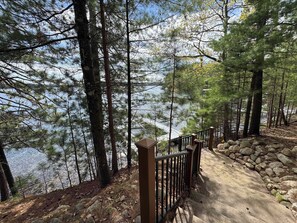 A forested area with a stone pathway leading to a body of water. - Stack's Back Bay Retreat (Minocqua)