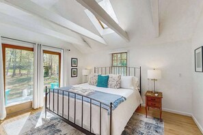Une chambre avec un puits de lumière, un lit avec une tête de lit, une table de chevet et une fenêtre avec des rideaux.