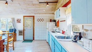 A kitchen with wooden cabinets, a sink, and a dining area with a table and chairs.