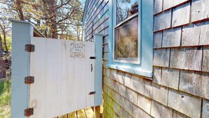 A utility box attached to a house with a sign requesting to bolt the shower door.