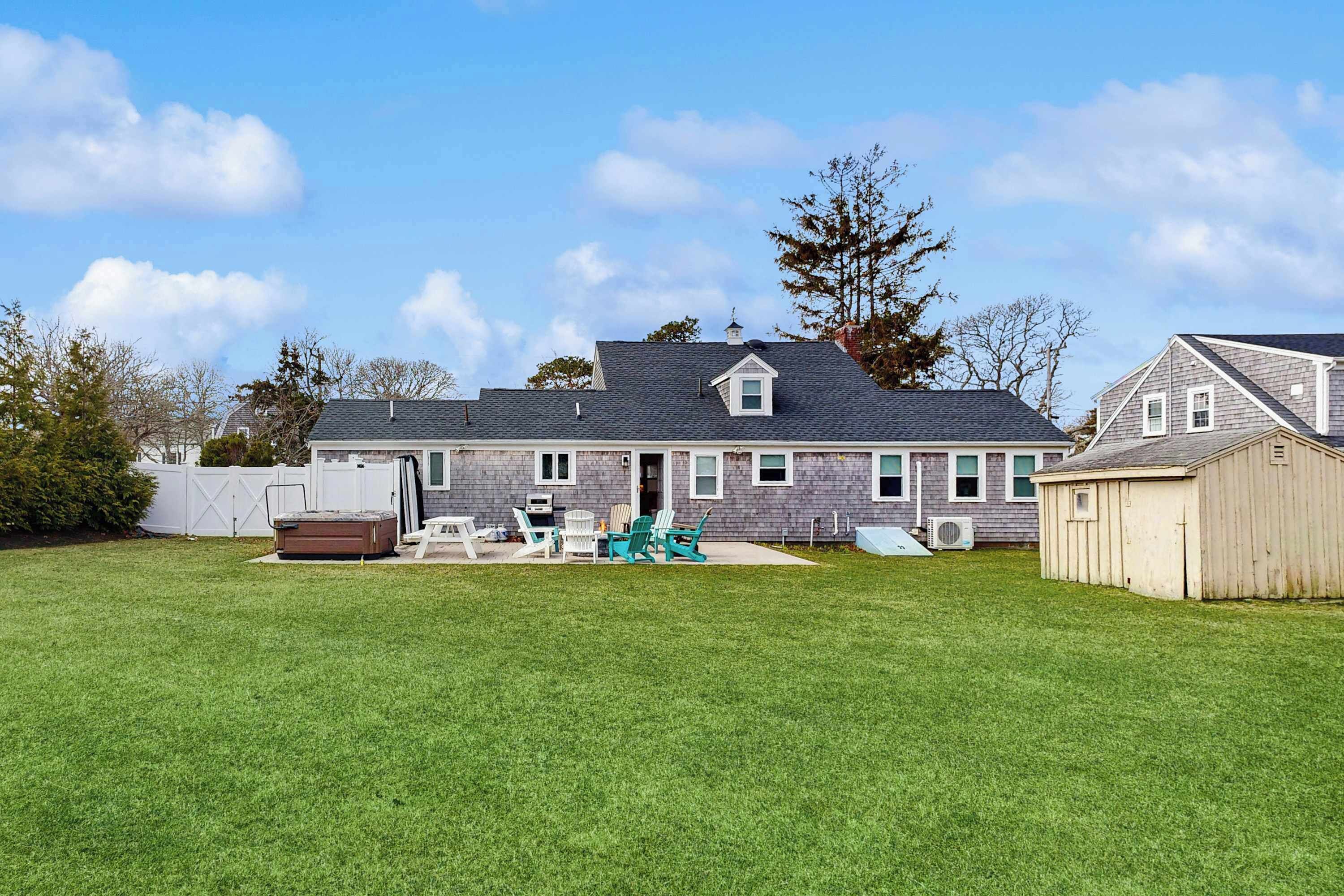 A two-story house with a covered patio, a shed, and a fenced yard.