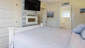 Een slaapkamer met een bed, een open haard, een televisie en een deur met de tekst 'CAPE COD'.