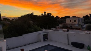 Ein Pool auf dem Dach mit freiem Blick auf den Sonnenuntergang und die umliegenden Gebäude.