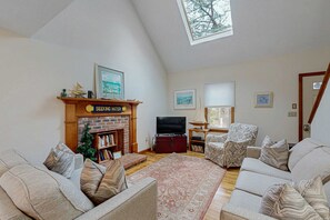 A living room with a fireplace, a television, two sofas, a patterned rug, and a skylight. - Dog friendly home w/ deck and private gas grill - on the bay side of the Cape (South Dennis)