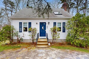 A white house with blue shutters, a blue door, and a small porch with steps. - Dog friendly home w/ deck and private gas grill - on the bay side of the Cape (South Dennis)