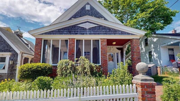 A two-story house with a gabled roof, a front porch, and a picket fence. - Charming apartment in the heart of town with quick WiFi (Provincetown)