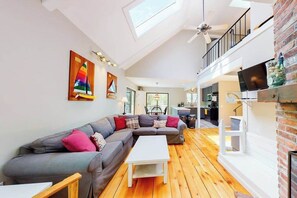A modern living room with a sectional sofa, a white coffee table, and a wooden floor.