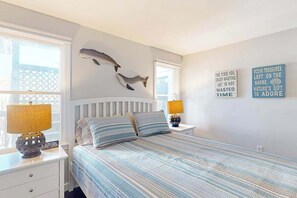 Une chambre à coucher comprenant un lit, deux tables de chevet, une horloge murale et deux lampes fixées au mur.