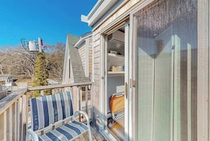 A wooden deck with a chair, a sliding glass door, and a utility meter.
