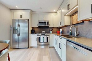 A modern kitchen with stainless steel appliances, white cabinetry, and a wooden countertop. - Provincetown Getaway, bikes, rooftop deck, EV Charger, Work remotely (Provincetown)