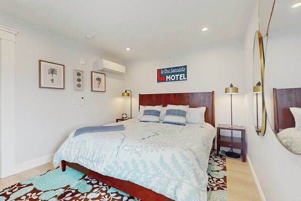 A bedroom with a bed, bedside tables, a mirror, and a sign indicating it's part of the 'To the Sandside Motel.' - Provincetown Getaway, bikes, rooftop deck, EV Charger, Work remotely (Provincetown)