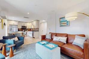 A modern living room with a sofa, coffee table, and a painting on the wall. - Provincetown Getaway, bikes, rooftop deck, EV Charger, Work remotely (Provincetown)