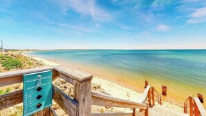 Un malecón de madera que lleva a una playa con cielos despejados.