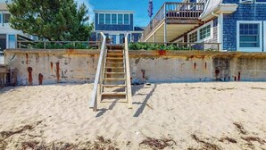 A beach with a wooden ladder leading to a building with a balcony.