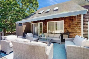 A covered patio with wicker furniture, a glass door, and a small table.