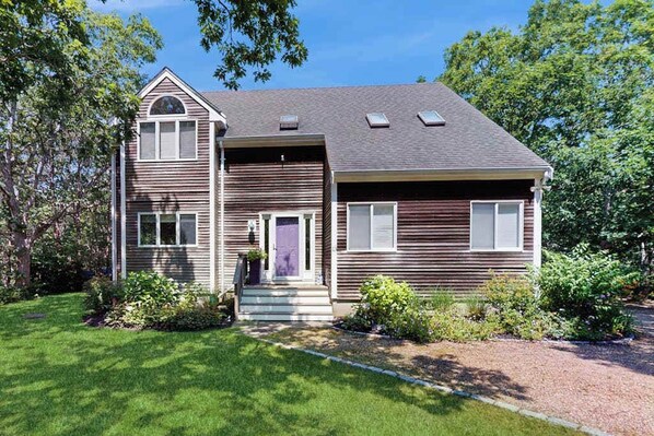 A two-story house with a front porch, a garage, and a small garden.