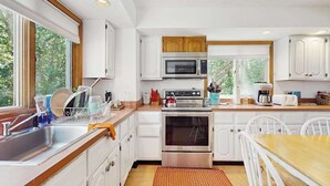 Una cocina moderna con armarios blancos, electrodomésticos de acero inoxidable y encimera de madera.
