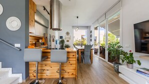 Una cucina moderna con isola centrale, pavimento in legno e un'ampia finestra vista giardino.