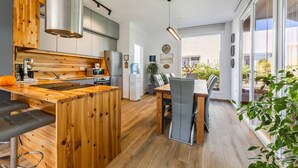 Una cucina moderna con isola in legno, un'area pranzo con tavolo e sedie, e un'ampia finestra che offre vista sull'esterno.