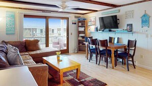 A living room with a sofa, coffee table, and dining area with chairs and a TV.