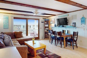 A living room with a sofa, coffee table, and dining area with chairs and a TV.