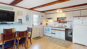 A kitchen with wooden chairs, a dining table, white cabinets, a built-in oven, and a refrigerator.