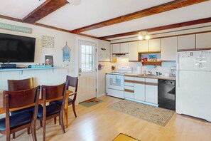 A kitchen with wooden chairs, a dining table, white cabinets, a built-in oven, and a refrigerator.