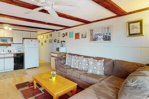 A living room with a brown sofa, wooden coffee table, and a ceiling fan.