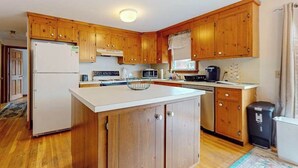 Une cuisine avec des meubles de rangement en bois, un réfrigérateur, un four à micro-ondes, une cuisinière et un évier.