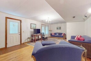 Ein Wohnzimmer mit einer Couch, einem Sessel, einem Fernseher und einem kleinen Tisch.