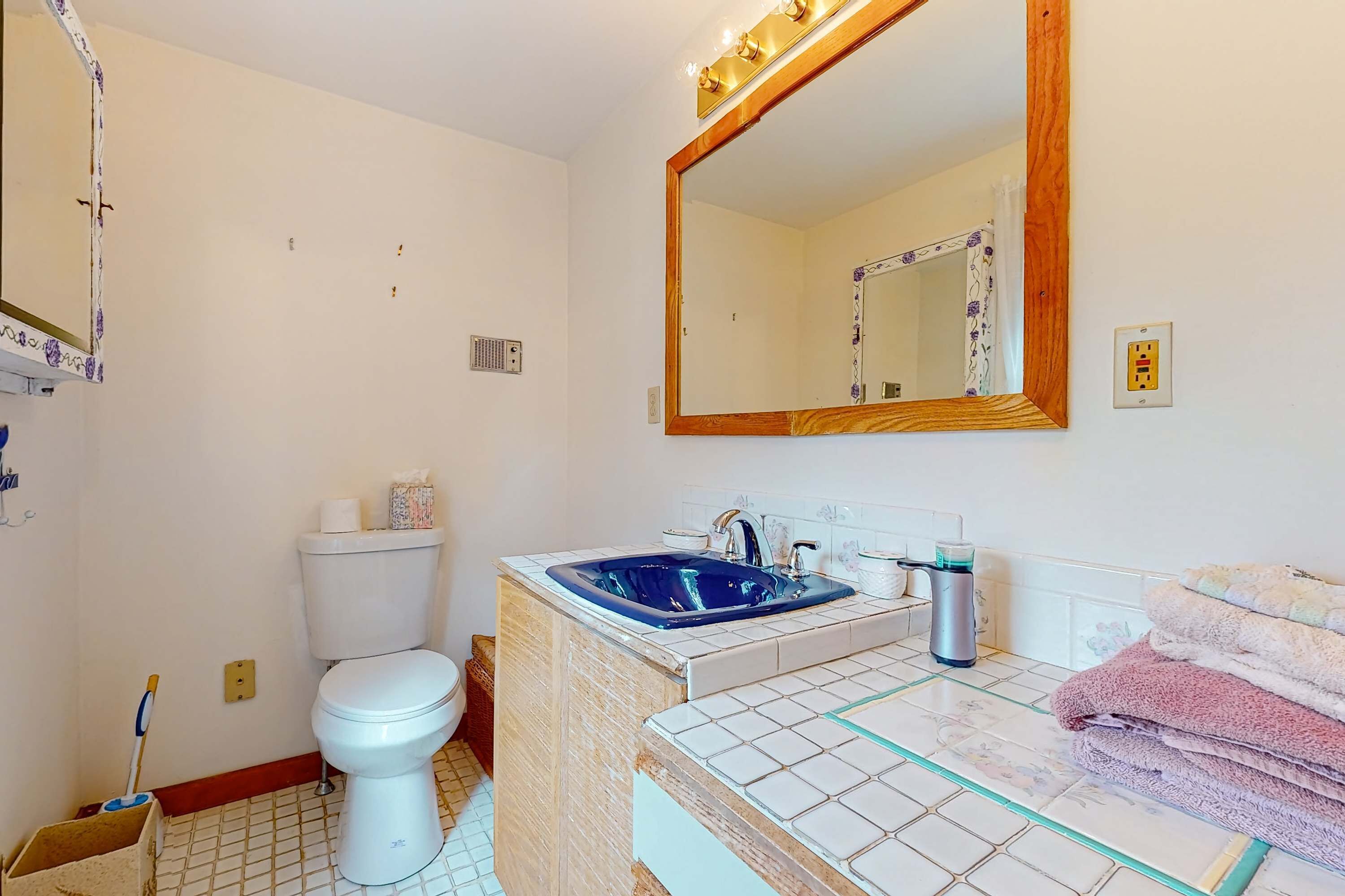 A bathroom with a toilet, sink, mirror, and towels.