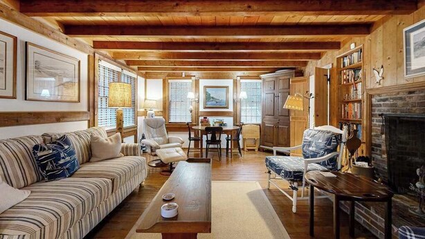 A cozy living room with a wooden ceiling, a sofa, a coffee table, a fireplace, and a bookshelf. - Quiet home near Pilgrim Lake with deck, W/D, AC, games, & large yard (Orleans)