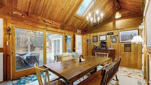 A wooden interior with a large dining table, benches, and a chandelier. - Quiet home near Pilgrim Lake with deck, W/D, AC, games, & large yard (Orleans)