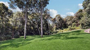 Un espace verdoyant bien entretenu, agrémenté d’arbres et bordé d’un mur en pierre.