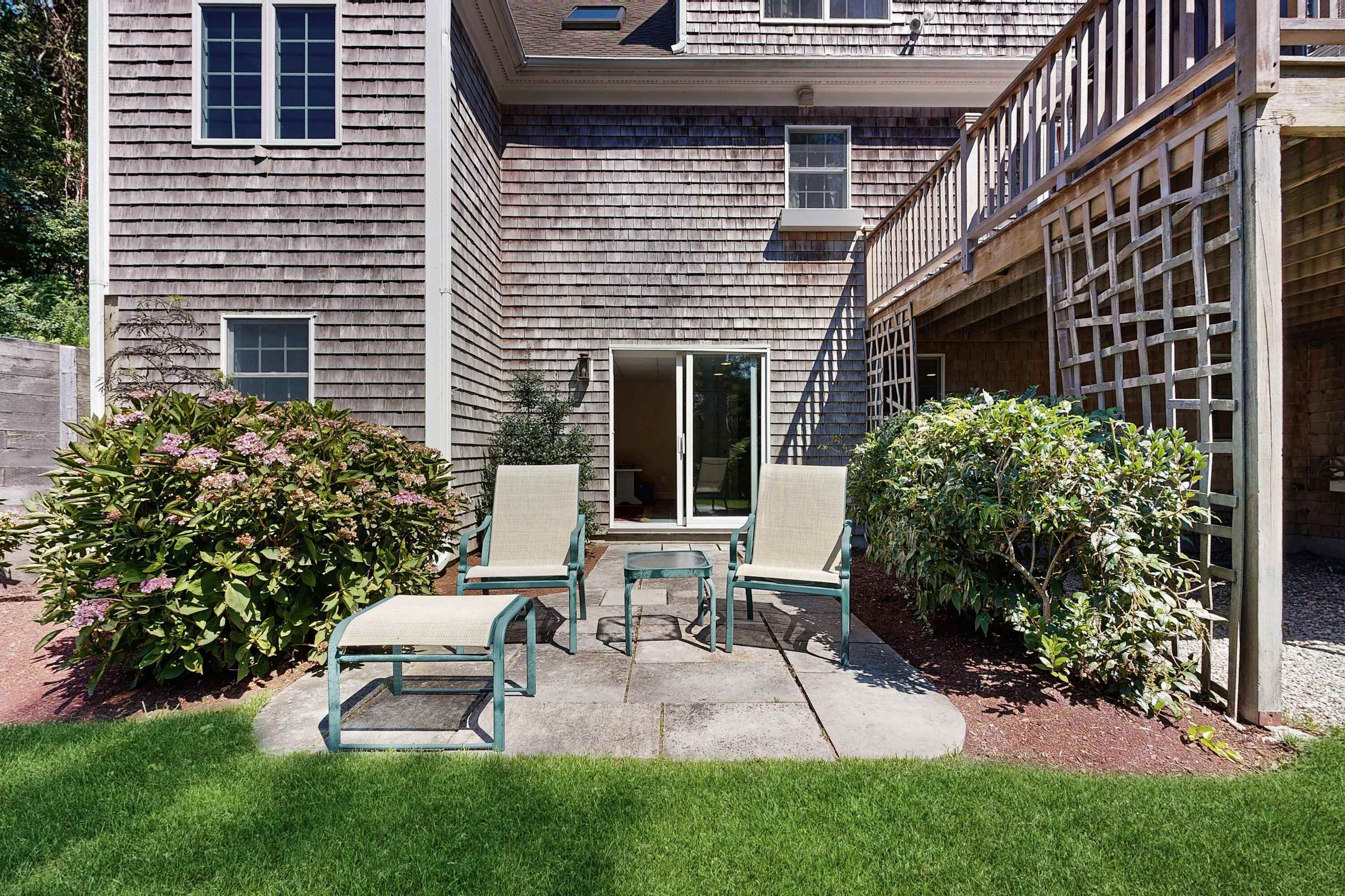 A residential building with a covered patio area, a sliding door entrance, and a small outdoor seating arrangement.
