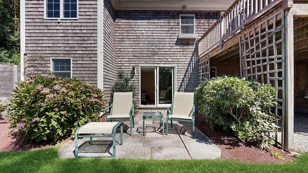 Un immeuble résidentiel doté d’un patio couvert, d’une entrée avec porte coulissante et d’un petit espace aménagé pour s’asseoir à l’extérieur.