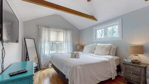 A bedroom with a bed, a nightstand, a mirror, a window, and a ceiling fan. - Skaket Beach escape: Corner-lot home with big yard - walk to Warm Bayside Shore (Orleans)