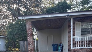 Et etplanshus med carport, indgangsdør og en lille forhave.