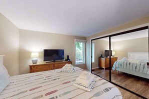 Une chambre à coucher comprenant un lit, un téléviseur, une commode et une porte coulissante donnant sur une autre pièce.