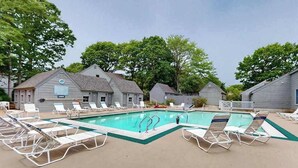 Ein Poolbereich mit Liegestühlen, einem Schwimmbecken und einer Reihe von Gebäuden im Hintergrund.