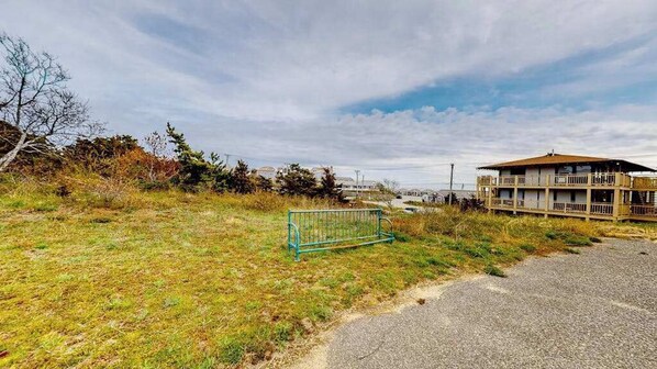 A building with a balcony, a fenced area, and a gravel path. - Ocean-view studio near golf with patio, beach gear, kitchenette, & partial AC (North Truro)