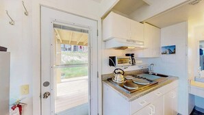 A compact kitchen with a gas stove, microwave, and kettle. - Ocean-view studio near golf with patio, beach gear, kitchenette, & partial AC (North Truro)